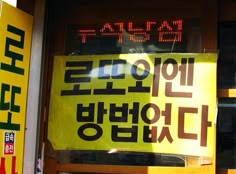 a yellow sign that is on the side of a building with writing in english and korean