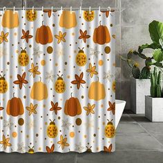 a shower curtain with pumpkins and leaves on it in front of a potted plant