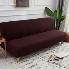 a couch sitting on top of a white rug next to a table and potted plant