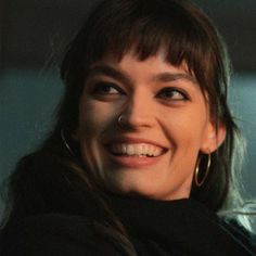 a woman smiling and wearing large hoop earrings