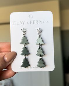 a pair of earrings with trees hanging from it's earwires in front of a card