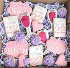 decorated cookies in a box with pink and purple decorations on them, including two wine glasses