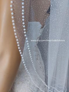 a mannequin wearing a wedding dress with pearls on it