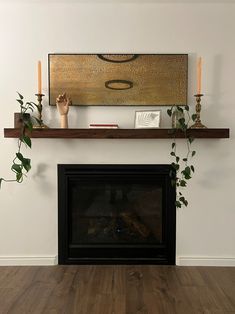 a living room with a fireplace and some candles on the mantles, along with plants