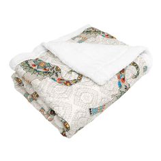 the white blanket is folded up on top of the other blankets, with an intricate design