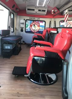 the inside of a bus with red seats and televisions on it's wall