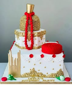 a three tiered cake with red and gold decorations