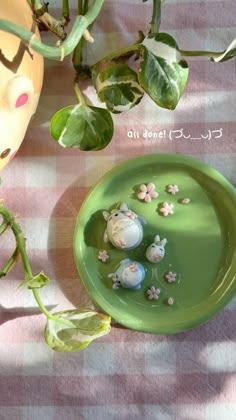 a green plate sitting on top of a checkered table cloth next to a potted plant