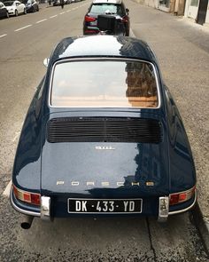 an old blue car parked on the side of the road with other cars behind it