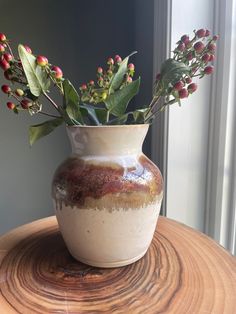 there is a vase with flowers in it on top of a wooden table next to a window