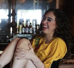 a woman sitting in front of a bar with her legs crossed and feet spread out