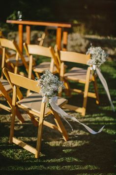 chairs with flowers tied to them sitting in the grass