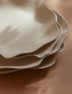 a stack of white plates sitting on top of a brown cloth covered table next to each other