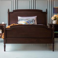 a bed with wooden headboard and foot board next to two nightstands on either side