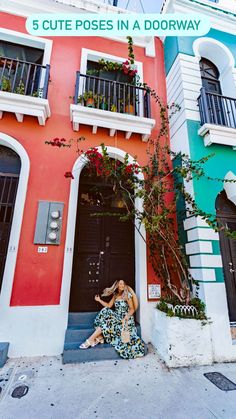 a woman sitting in front of a colorful building