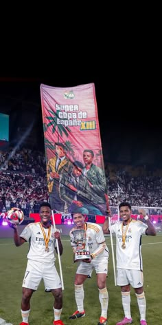 three soccer players are holding their trophies and posing for a photo in front of an audience