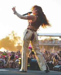 a woman standing on top of a stage with her arms out in front of the crowd