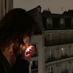 a woman is looking at her cell phone in front of the cityscape and buildings