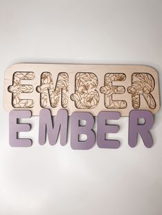 a wooden sign with the word ember carved into it's letters on a white wall