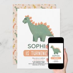 a person holding up a phone next to a card with an image of a dinosaur on it