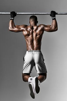 a man hanging upside down on a bar with his hands in the air while doing pull ups