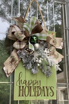 a green sign that says happy holidays hanging from the side of a building with decorations on it