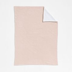 a pink and white blanket folded on top of each other with a white corner at the end