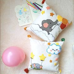 two pillows with animals and balloons on the floor next to a pink balloon, pencils, and other items