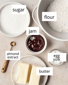 ingredients to make chocolate cake laid out on a table with flour, sugar, jam, and butter