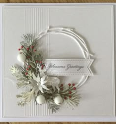 a christmas card with white flowers and greenery on the front, along with a ribbon that says grandma's greetings