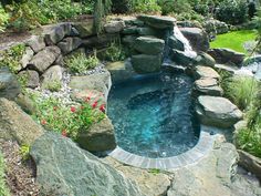 an outdoor pool surrounded by rocks and flowers