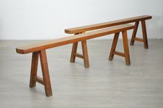 two wooden benches sitting next to each other on top of a hard wood floored floor