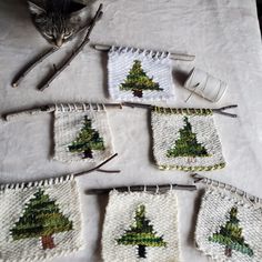 knitted christmas tree coasters on a table with a cat sitting next to them