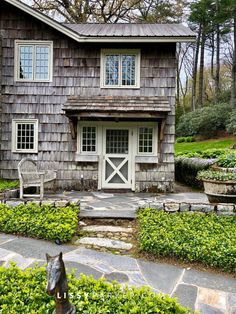 a horse statue sitting in front of a wooden house with white windows and shutters