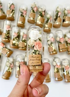 a person holding up a tiny bottle with flowers in it's corks on the side