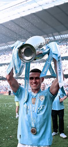 a man holding up a trophy on top of a field