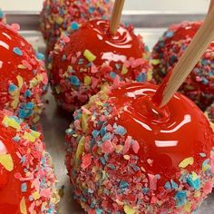 red apples with sprinkles and wooden sticks on them are ready to be eaten