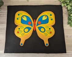 a butterfly shaped cookie sitting on top of a black surface next to green plants and a potted plant