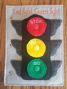 a close up of a traffic light made out of felt on a wooden surface with the words red light green light