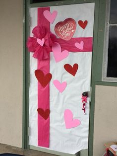 a door decorated with paper hearts and a pink ribbon