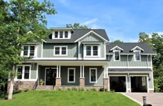 a large gray house with lots of windows on it's sides and two car garages