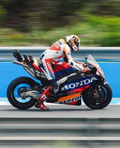 a man riding on the back of a motorcycle down a race track