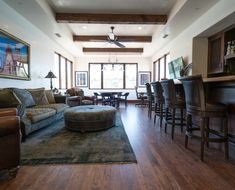 a living room filled with furniture next to a dining room table and bar stools