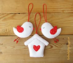 two felt bird ornaments hanging on a wooden wall