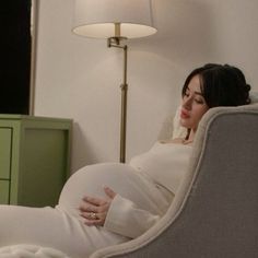 a pregnant woman sitting in a chair with her hands on her stomach