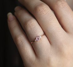 a woman's hand with a pink diamond ring on top of her left hand