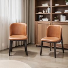 two brown chairs sitting in front of a book shelf