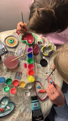 two children sitting at a table with art supplies