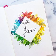 an open notebook with the words hello june written on it and colorful leaves around it