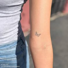 a woman's arm with a small butterfly tattoo on the left side of her arm